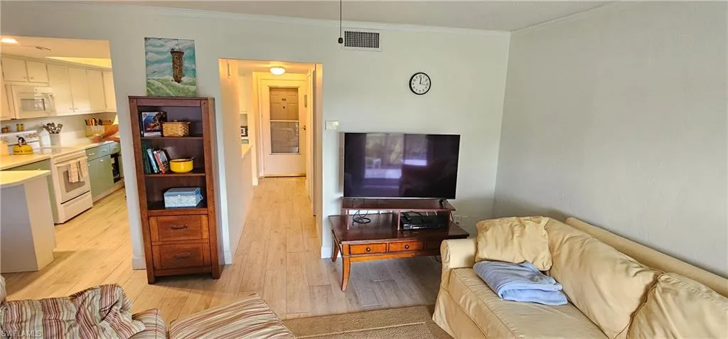 Living room featuring light hardwood / wood-style flooring and ornamental molding