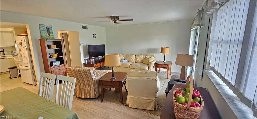 Living room featuring crown molding, ceiling fan, and light hardwood / wood-style floors