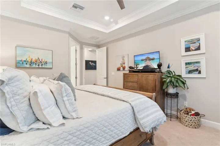 Carpeted bedroom featuring crown molding, a ceiling fan, and baseboards