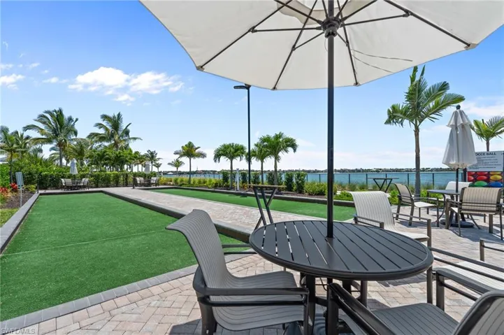 View of patio featuring a bocce ball area, a water view, and outdoor dining space