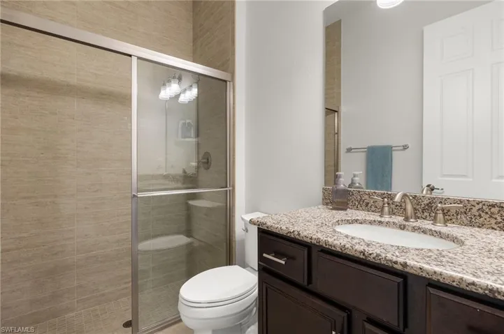 Bathroom with vanity, a shower stall, and toilet