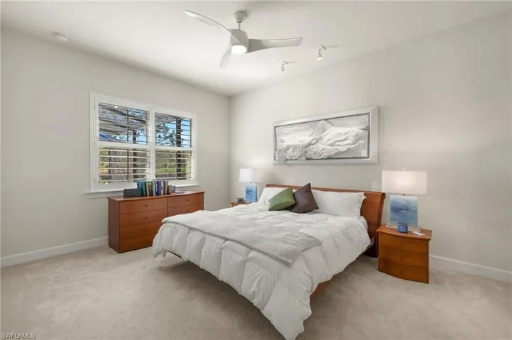 Bedroom featuring light carpet, ceiling fan, and baseboards