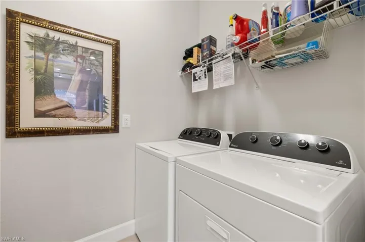 Washroom with washing machine and clothes dryer, laundry area, and baseboards
