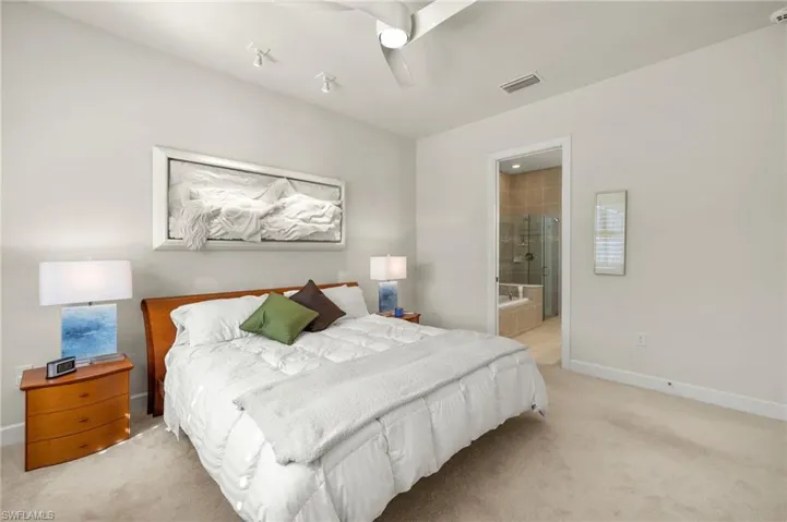 Bedroom with visible vents, ensuite bathroom, a ceiling fan, baseboards, and light colored carpet