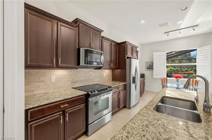 Kitchen with light stone countertops, visible vents, a sink, appliances with stainless steel finishes, and backsplash