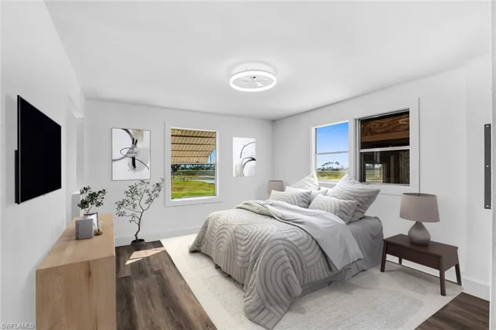 Bedroom with dark wood finished floors and baseboards
