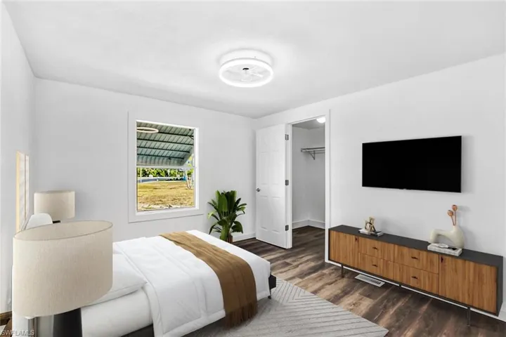 Bedroom with a spacious closet and dark wood-style floors