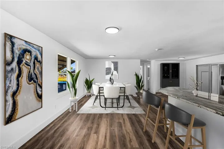 Dining space with dark wood-style flooring and baseboards