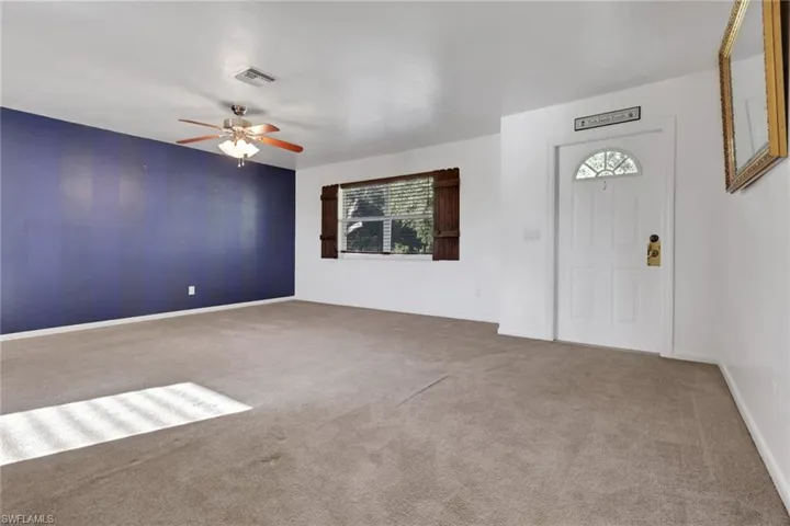 Carpeted foyer featuring ceiling fan and baseboards