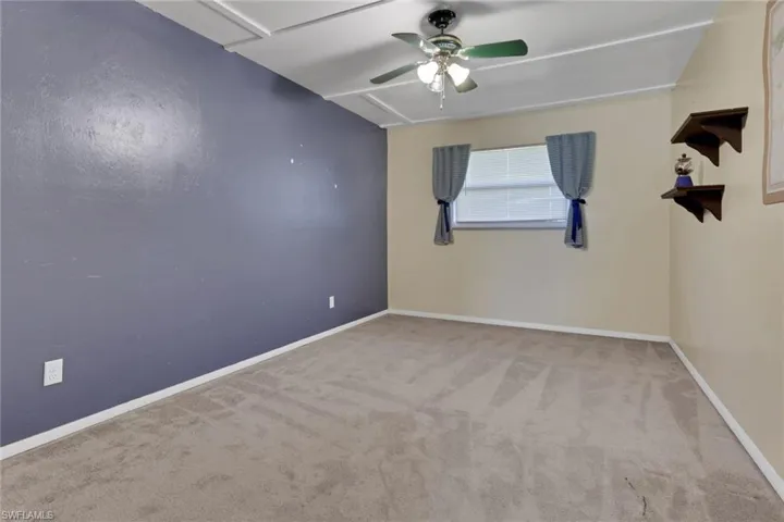 Empty room with light carpet and a ceiling fan