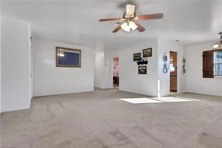 Unfurnished living room featuring a ceiling fan and light carpet