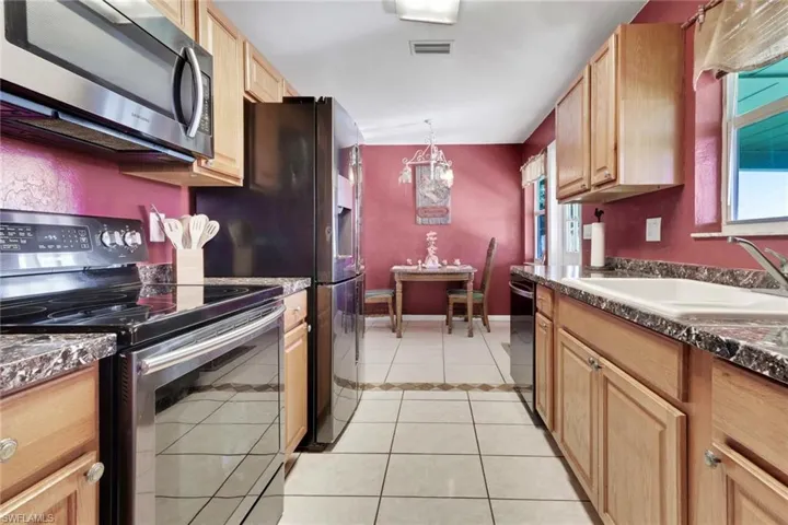 Kitchen featuring stainless steel appliances, light tile patterned flooring, healthy amount of natural light, and decorative light fixtures