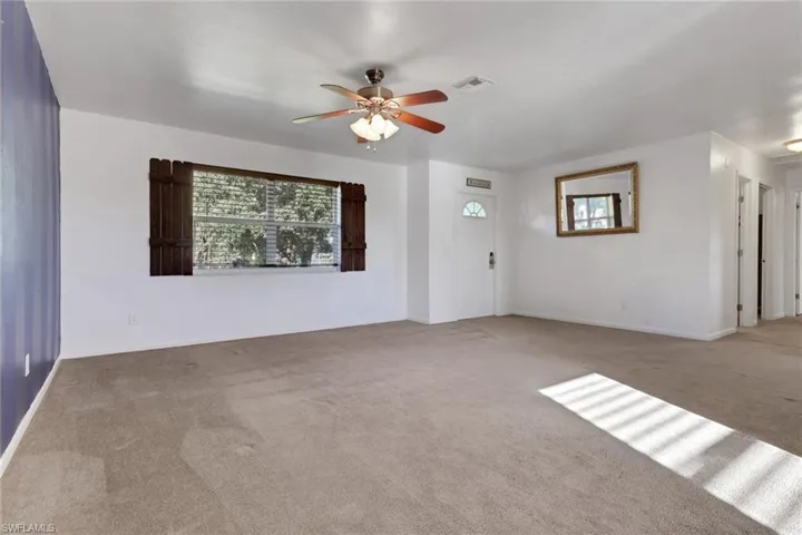 Unfurnished living room featuring plenty of natural light, carpet, and a ceiling fan