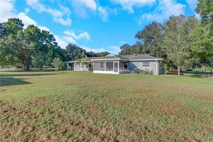Back of house with a yard and a sunroom
