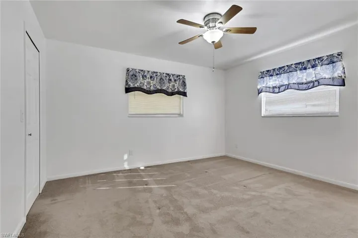 Empty room featuring light colored carpet and a ceiling fan
