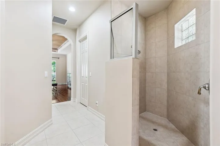Full bath with tile patterned flooring, baseboards, visible vents, and walk in shower