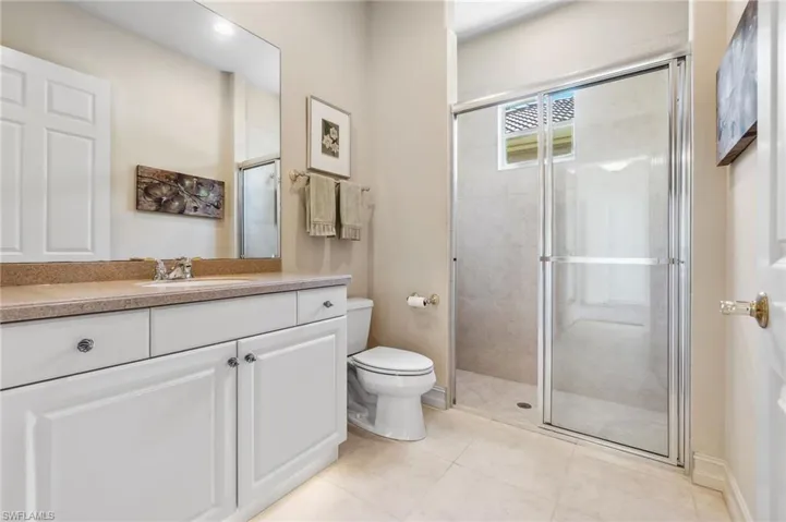 Full bath with tile patterned floors, toilet, and a stall shower