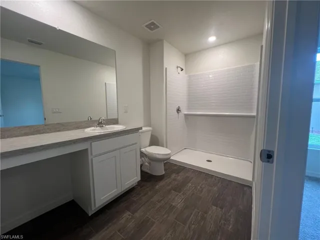 Bathroom featuring a shower, vanity, and wood finished floors