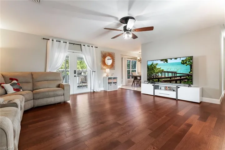 Living area with ceiling fan, wood finished floors, and french doors
