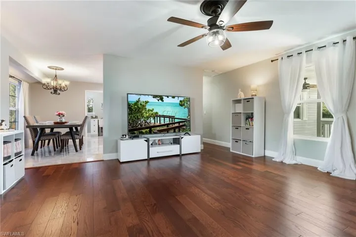 Living area featuring a chandelier, hardwood / wood-style flooring, a ceiling fan, and baseboards