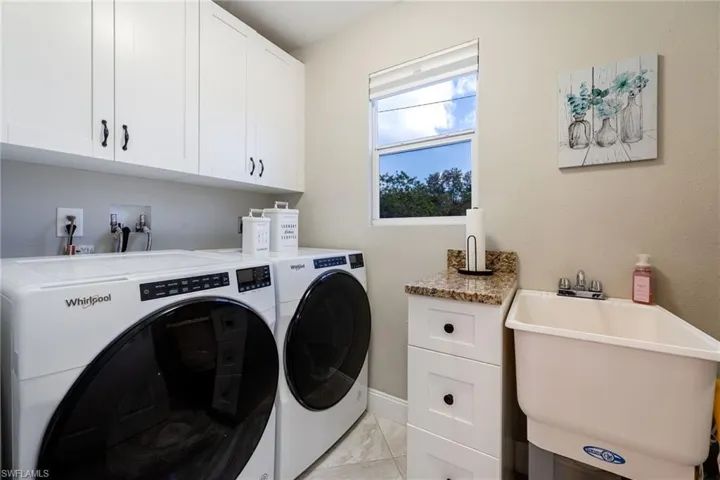 Laundry room featuring independent washer and dryer, cabinet space, and baseboards