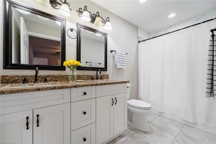 Bathroom with double vanity, toilet, shower / bath combo, and recessed lighting