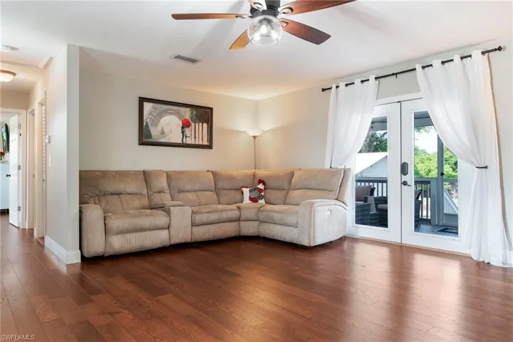 Living area featuring french doors, dark wood-style floors, a ceiling fan, and baseboards