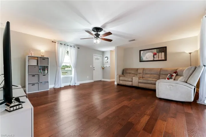 Living room featuring a ceiling fan, dark wood-style floors, and baseboards