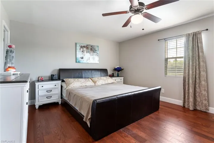 Bedroom featuring dark wood-style flooring, baseboards, and a ceiling fan
