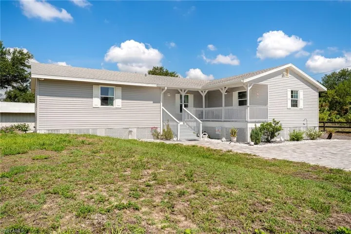 Ranch-style home featuring covered porch and a front yard