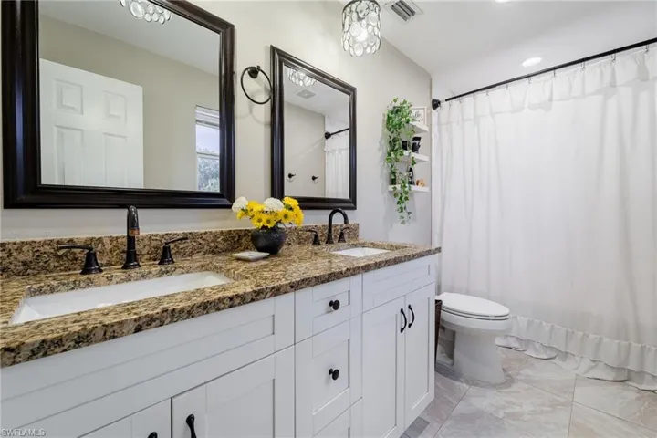 Bathroom featuring double vanity, toilet, and recessed lighting