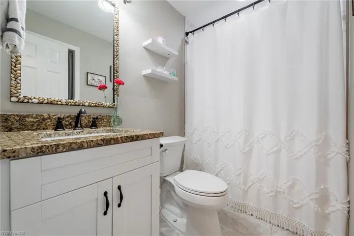 Bathroom with vanity, toilet, tile patterned floors, and curtained shower