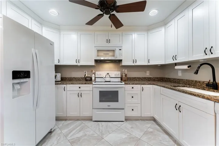 Kitchen with white appliances, a sink, ceiling fan, white cabinets, and recessed lighting