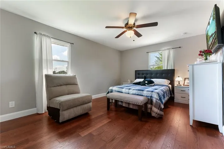Bedroom with dark wood-style flooring, baseboards, and a ceiling fan