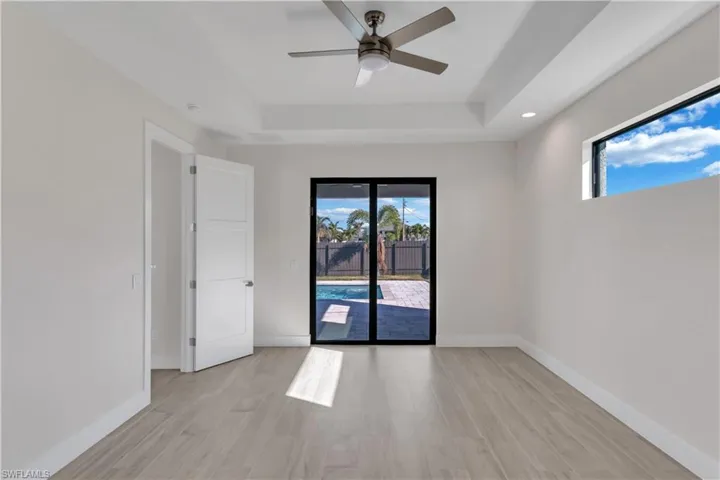 Spare room with ceiling fan, a raised ceiling, and light wood-type flooring