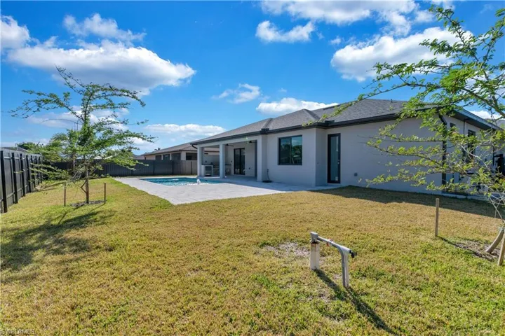 Back of house with a lawn and a patio