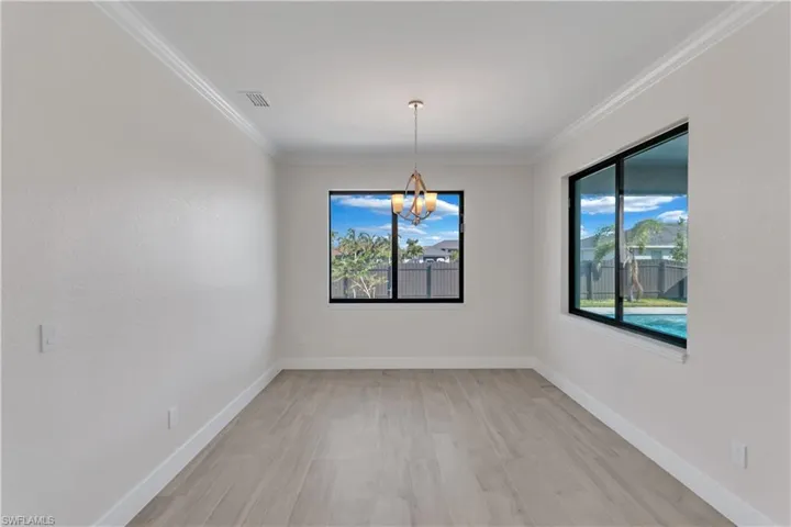 Spare room with a chandelier, light hardwood / wood-style flooring, and crown molding