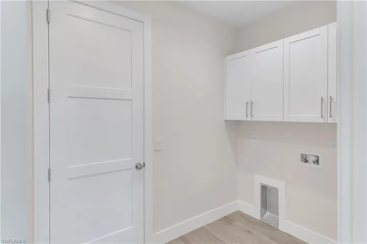 Laundry room with hookup for an electric dryer, light hardwood / wood-style floors, cabinets, and hookup for a washing machine
