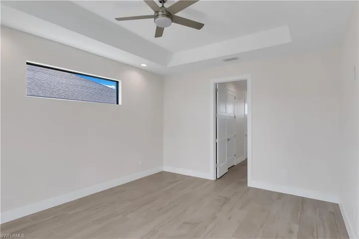 Empty room featuring light hardwood / wood-style floors, a raised ceiling, and ceiling fan