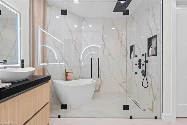 Full bathroom featuring a marble finish shower, stone wall, vanity, a soaking tub, and marble tiled flooring