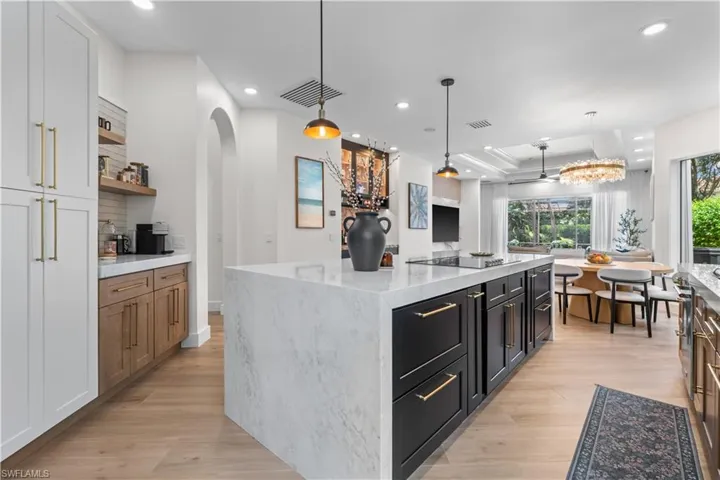 Kitchen featuring a tray ceiling, light wood-style floors, open shelves, recessed lighting, and a kitchen island