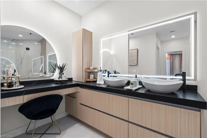 Bathroom featuring a marble finish shower, recessed lighting, and double vanity