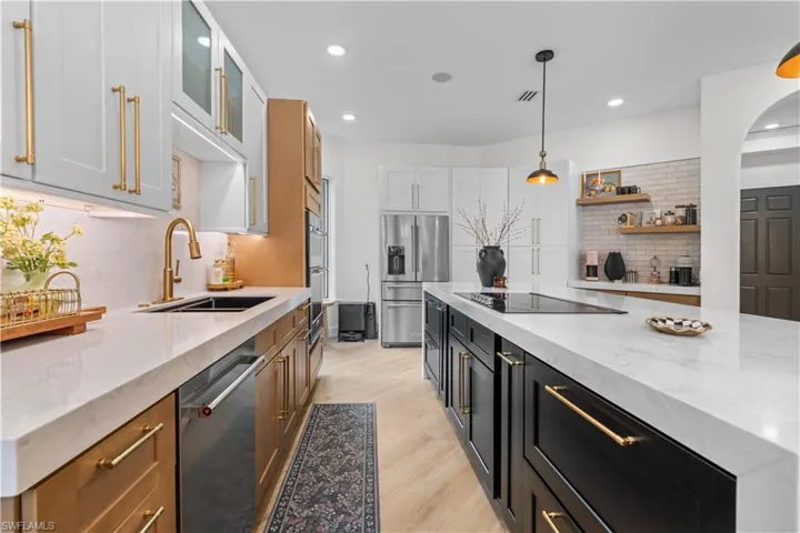 Kitchen featuring tasteful backsplash, hanging light fixtures, light wood finished floors, appliances with stainless steel finishes, and recessed lighting