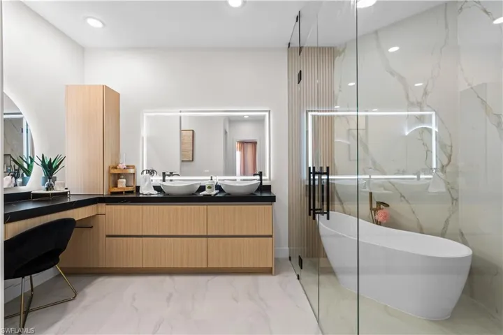 Bathroom featuring marble finish floors, a soaking tub, double vanity, recessed lighting, and a marble finish shower