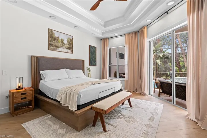 Bedroom with access to outside, crown molding, a raised ceiling, light wood finished floors, and ceiling fan