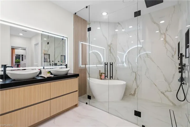 Bathroom with a marble finish shower, double vanity, a freestanding tub, marble tiled flooring, and recessed lighting