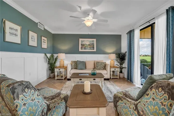 Living room with ceiling fan, crown molding, and light tile patterned floors