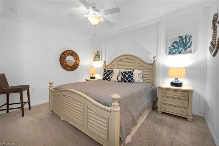 Carpeted bedroom featuring ceiling fan and ornamental molding
