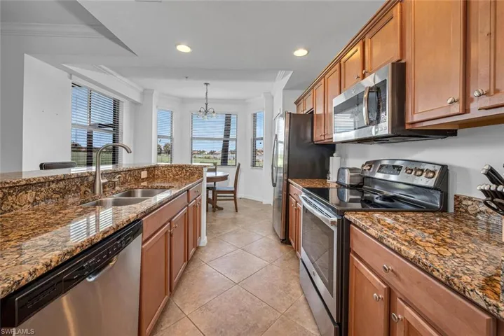 Kitchen featuring ornamental molding, stainless steel appliances, dark stone countertops, and sink