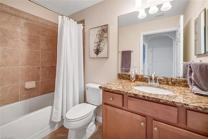 Full bathroom featuring vanity, shower / tub combo, toilet, and tile patterned flooring